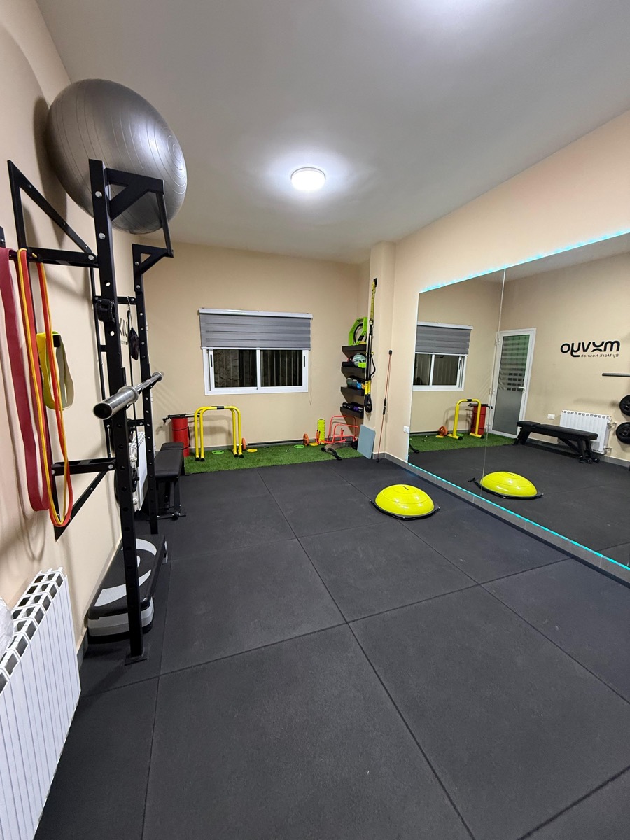 The Movyo rehab gym: rubber floor, squat rack, mirror wall and balance gear