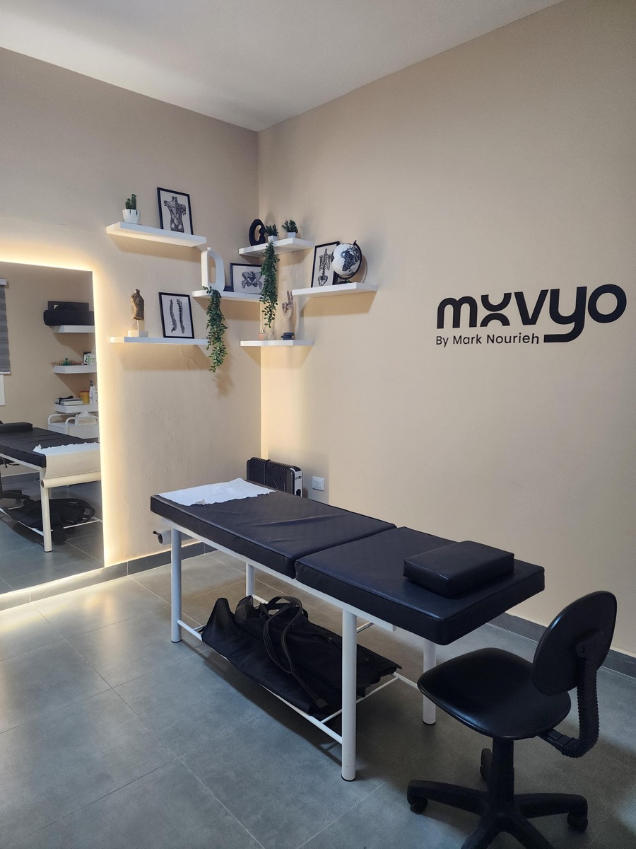 Movyo treatment room with table, anatomy prints and the Movyo logo on the wall